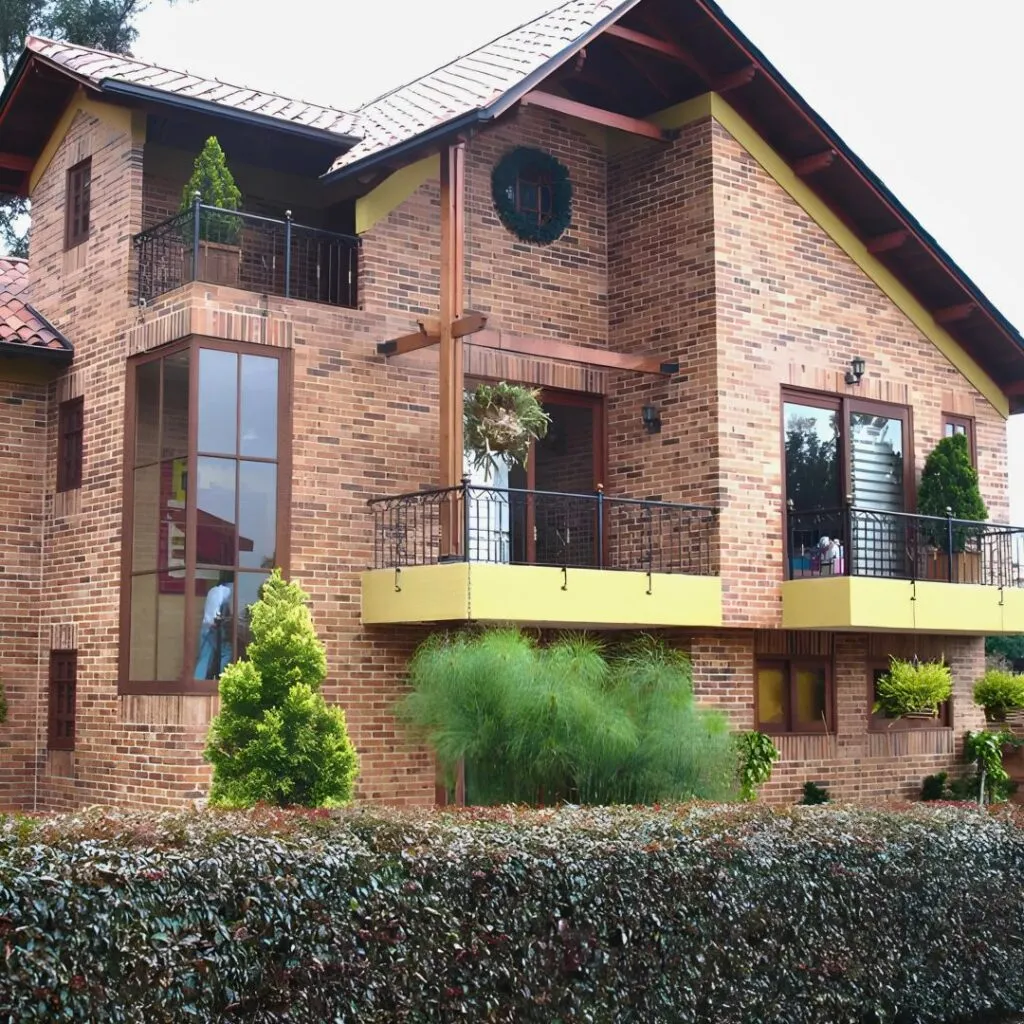 Fachada de casa campestre remodelada, con balcón en ladrillo visto y carpintería en madera, ejemplo de diseño y remodelación de casas en Bogotá